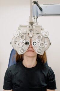 A Caucasian woman undergoing a vision test using a phoropter in a clinic.