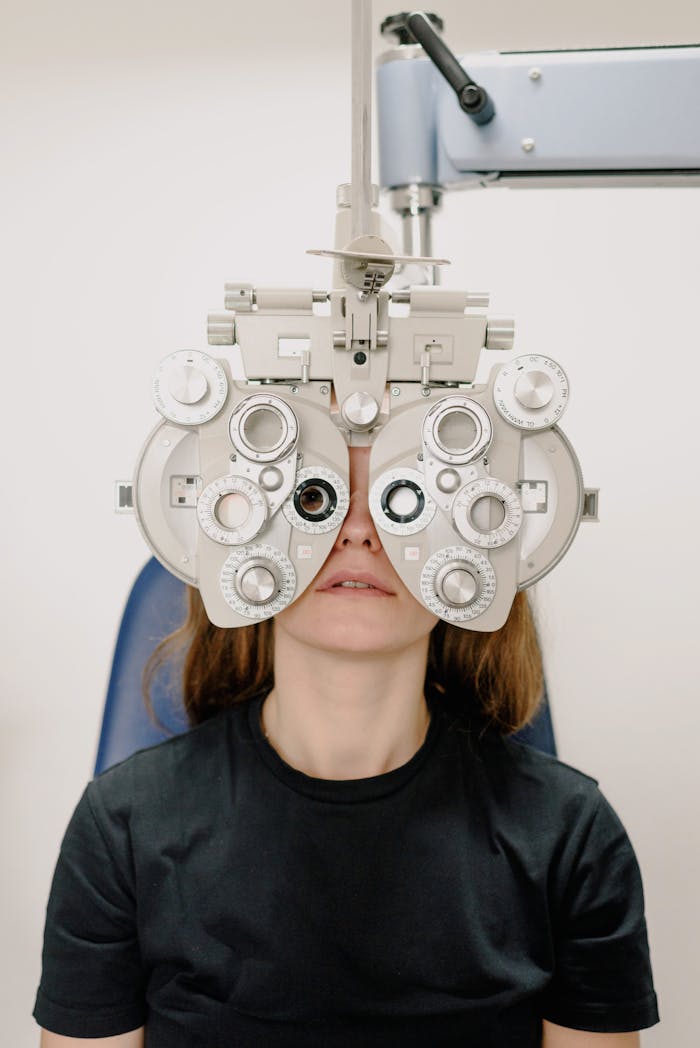 A Caucasian woman undergoing a vision test using a phoropter in a clinic.